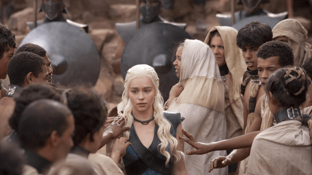 Game of Thrones S3E10 "Mhysa" episode guide featured image showing a pale-haired queen facing a crowd in a sunlit city square